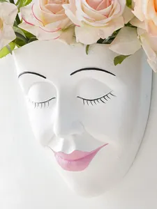 Detailed macro shot of white resin face wall planter with closed eyes and pink lips