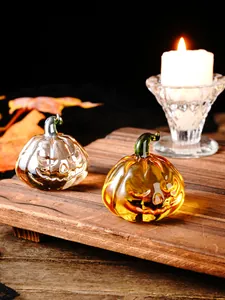 Close-up of decorative glass pumpkin ornaments with warm candle light for Halloween