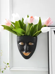 Close-up of black resin human face wall-hanging flower pot with artificial tulips