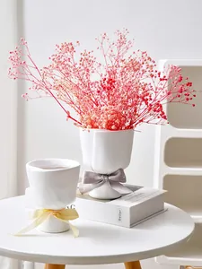 Elegant detailed view of two white hand-bouquet resin vases with pink baby's breath