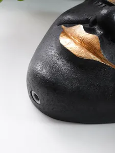 Macro detail showing the textured black resin and golden lips of this artistic face planter