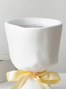 Close-up of a white hand-held bouquet shaped resin vase with a yellow ribbon