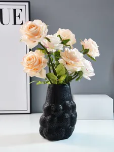 Detailansicht einer schwarzen perforierten ABS-Harzvase mit pfirsichfarbenen Rosen