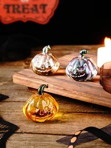 Detail shot of three creative glass pumpkins for Halloween decor on a wooden board