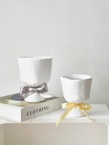 Detail of Nordic bouquet-shaped white resin vases with decorative silk ribbons