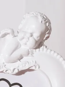 Close-up macro view of the intricate white resin angel carving on a vintage photo frame.
