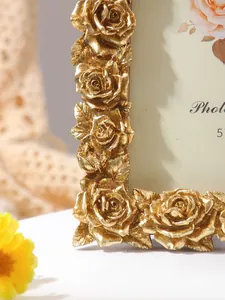 Close-up detail of a golden vintage photo frame with intricate rose flower carvings decoration