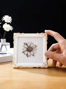 Detailansicht eines verzierten europäischen Bilderrahmens in Weiß und Gold mit Blumenkunst.