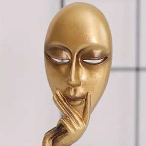 Macro detail of a gold abstract 'Silence is Golden' resin mask sculpture decoration