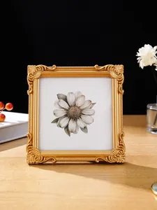 Detailansicht eines verzierten goldenen Vintage Relief Fotorahmens auf Holztisch