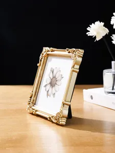 Nahaufnahme eines eleganten goldgeprägten Fotorahmens mit Blumenkunst auf Holztisch