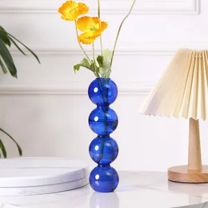 Detailansicht einer modernen blauen Glaskugelvase mit gelben Mohnblumen auf einem Tisch