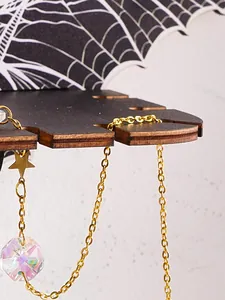 Close-up of Halloween bat wing wooden shelf showing gold star and crystal hanging