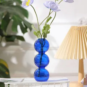 Nahaufnahme einer blauen kreativen Glasvase mit dreifach verbundenen Kugeln
