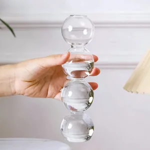 Detailansicht einer Hand, die eine moderne Glasvase mit vier verbundenen Kugeln hält