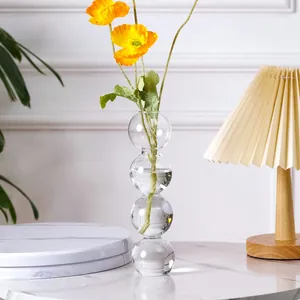 Detailansicht der kreativen Bubble-Glasvase mit gelbem Mohn und warmer Schreibtischlampe