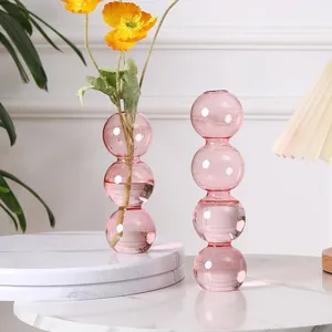 Detailansicht von rosa Glasvasen mit gelben Mohnblumen auf einem Marmortisch