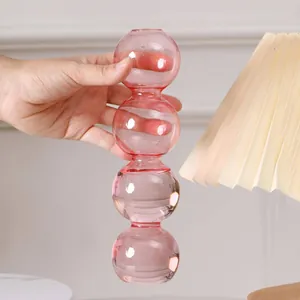 Hand hält eine rosa Glasvase mit vier verbundenen Kugeln für die Innendekoration
