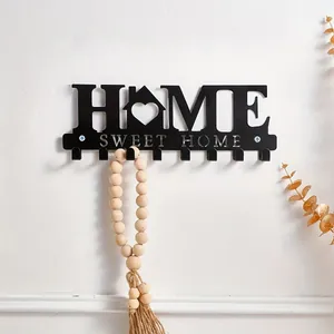 Detailed view of black metal 'Home Sweet Home' wall hook with wooden bead decor.