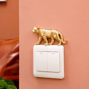 Close-up of golden resin leopard decoration placed on a white light switch