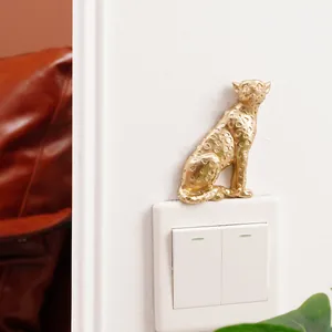 Detail shot of a golden resin leopard figurine decorating a white light switch.
