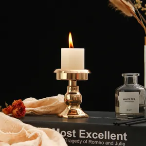 Close-up of a minimalist gold metal candle holder on a book with warm candlelight.