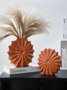 Macro view of two modern terracotta resin shell-shaped vases with pleated radial texture
