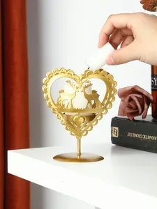 Primer plano de una mano colocando una vela en el portavelas dorado con forma de corazón
