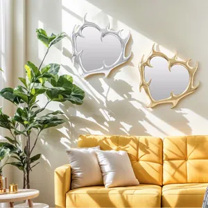 Due specchi da parete artistici a forma di cuore in oro e argento sopra un divano giallo