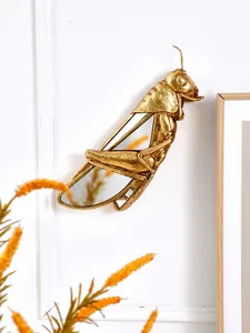 Vue détaillée d'une décoration murale en résine dorée en forme de sauterelle avec miroirs