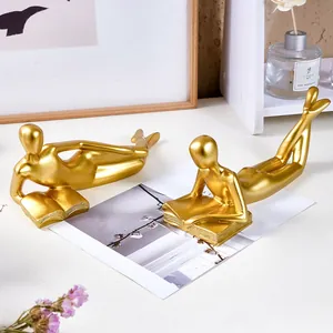 Detailed shot of two golden reader figurines in a minimalist home decor setting.