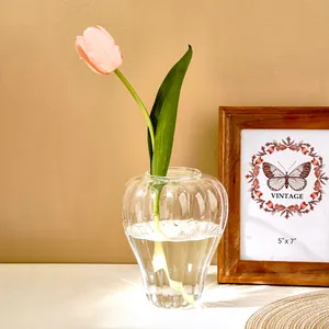 Elegante jarrón de cristal con forma de calabaza y tulipán rosa en hogar moderno