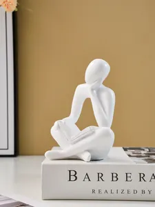 Close-up of a minimalist white thinker figurine reading a book for modern home desktop decor