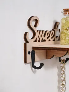 Detailopname van een houten sleutelrek voor de muur met metalen haak en gesneden Sweet-letters