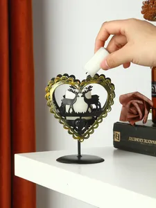 Mano colocando una vela blanca en un candelabro de hierro con forma de corazón