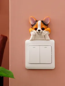 Close-up of cute 3D resin Corgi dog peeking over a white light switch on a pink wall