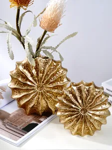 Macro detail showing the textured golden metallic finish of modern seashell resin vases