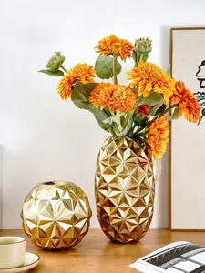 Detailopname van gouden geometrische vazen met zonnebloemen op een houten tafel