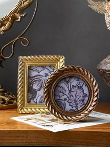 Vintage goldene Fotorahmen mit Spiralrand und floralem Einsatz auf einem Holztisch