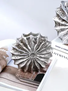 Detail view of the silver metallic texture and pleated design of a seashell resin vase