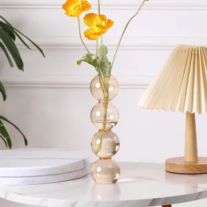 Nahaufnahme einer bernsteinfarbenen Glaskugelvase mit gelben Mohnblumen auf Marmor