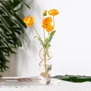 Detailansicht einer kreativen Glasvase mit leuchtend orangefarbenen Mohnblumen