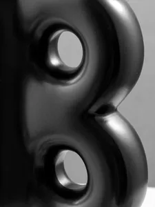 Dettaglio macro ravvicinato della texture nera opaca del vaso in resina a forma di B.