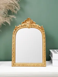 Nahaufnahme eines goldenen verzierten Harzrahmens auf einem weißen Tisch mit Dekor