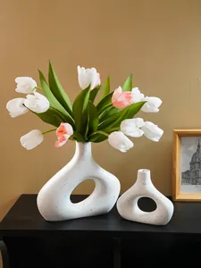 Moderne witte gespikkelde O-vormige harsvazen met kunsttulpen in een woonomgeving