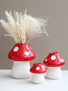 Detailed view of three red mushroom resin vases arranged on a white table surface.