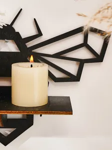 Detail view of a black geometric wooden bee shelf featuring a lit candle on its platform