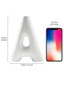 Detail view of A-shaped white resin vase with size markers and a phone for scale