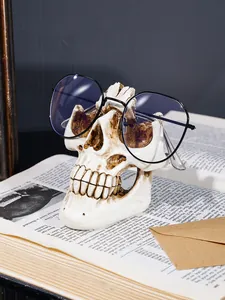 Detailansicht eines gotischen Totenkopf-Brillenhalters aus Harz auf einem alten Buch