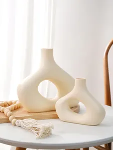 Close-up van een minimalistische Scandinavische O-vormige vaasenset van crèmekleurige hars